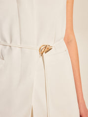 Gold belt buckle on white sleeveless vest close-up
