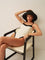 Woman wearing white swimsuit with black contrast straps, seated