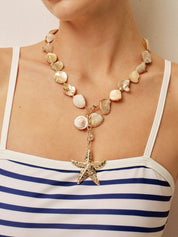 Necklace with gold starfish pendant and shell beads, front view on model
