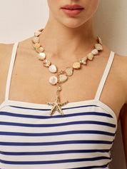 Necklace with gold starfish pendant and shell beads, close-up on model