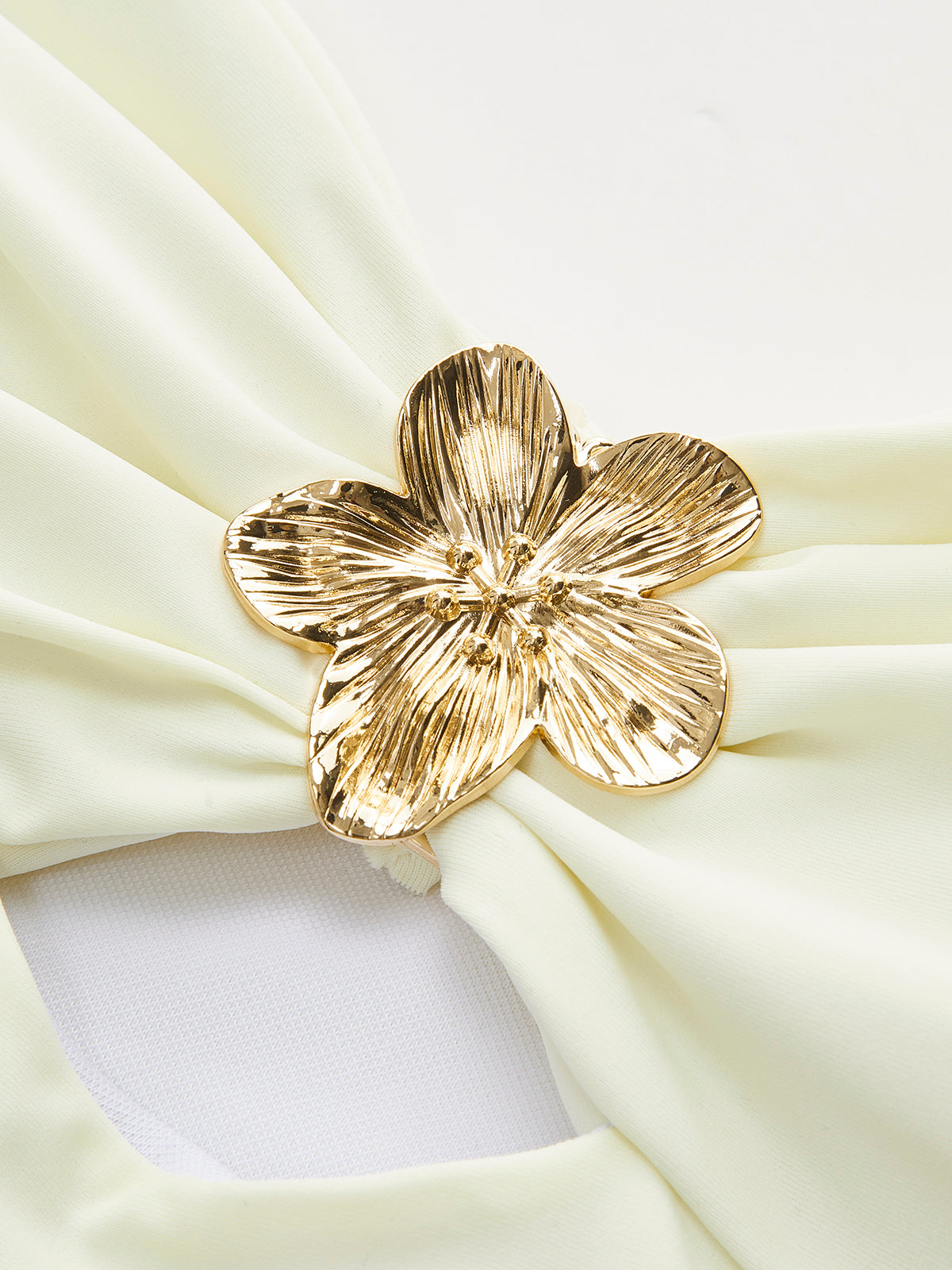 Gold flower detail on white one-piece swimsuit close-up