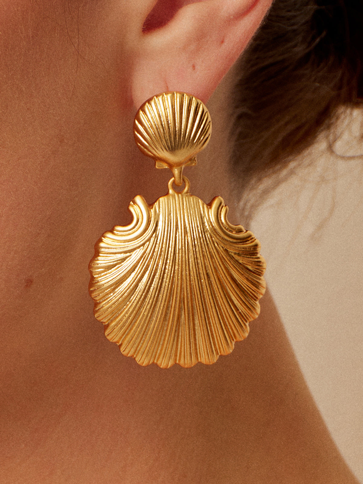 Gold shell-shaped earrings with textured detail, close-up front view