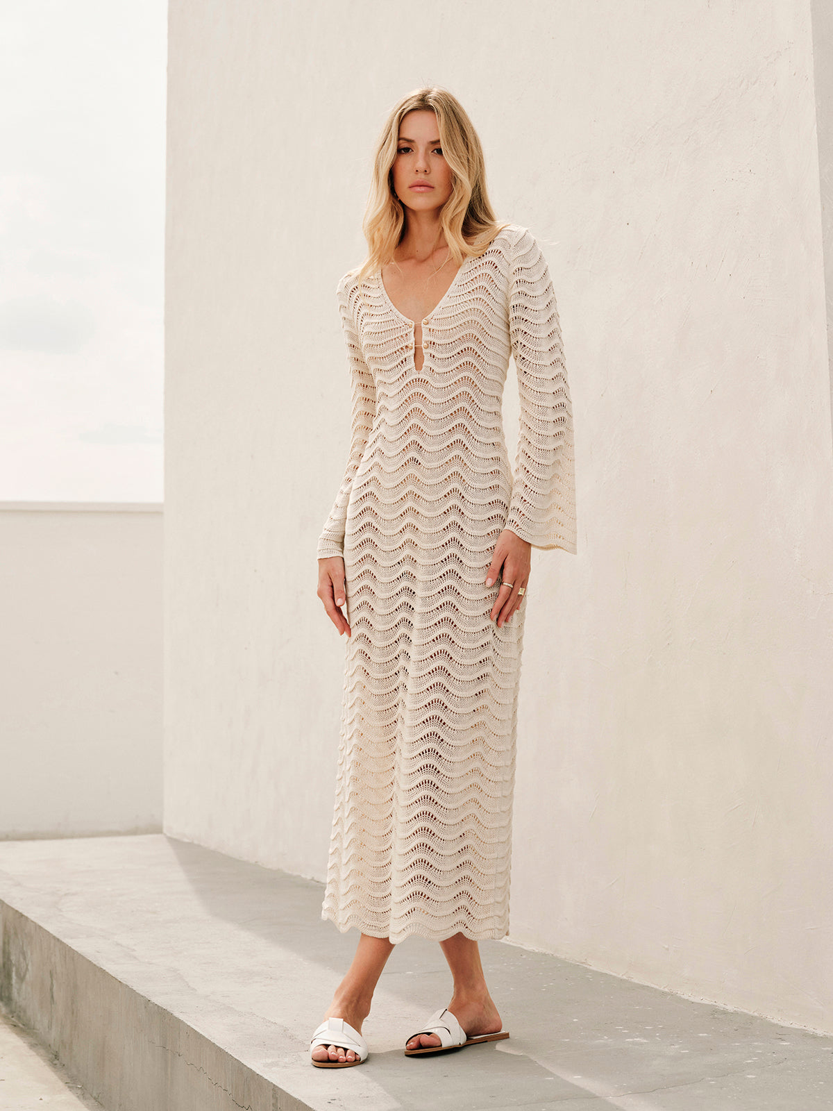 Cream lace dress with bell sleeves and white sandals full body view