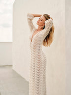Cream lace dress with bell sleeves and gold earrings arm raised