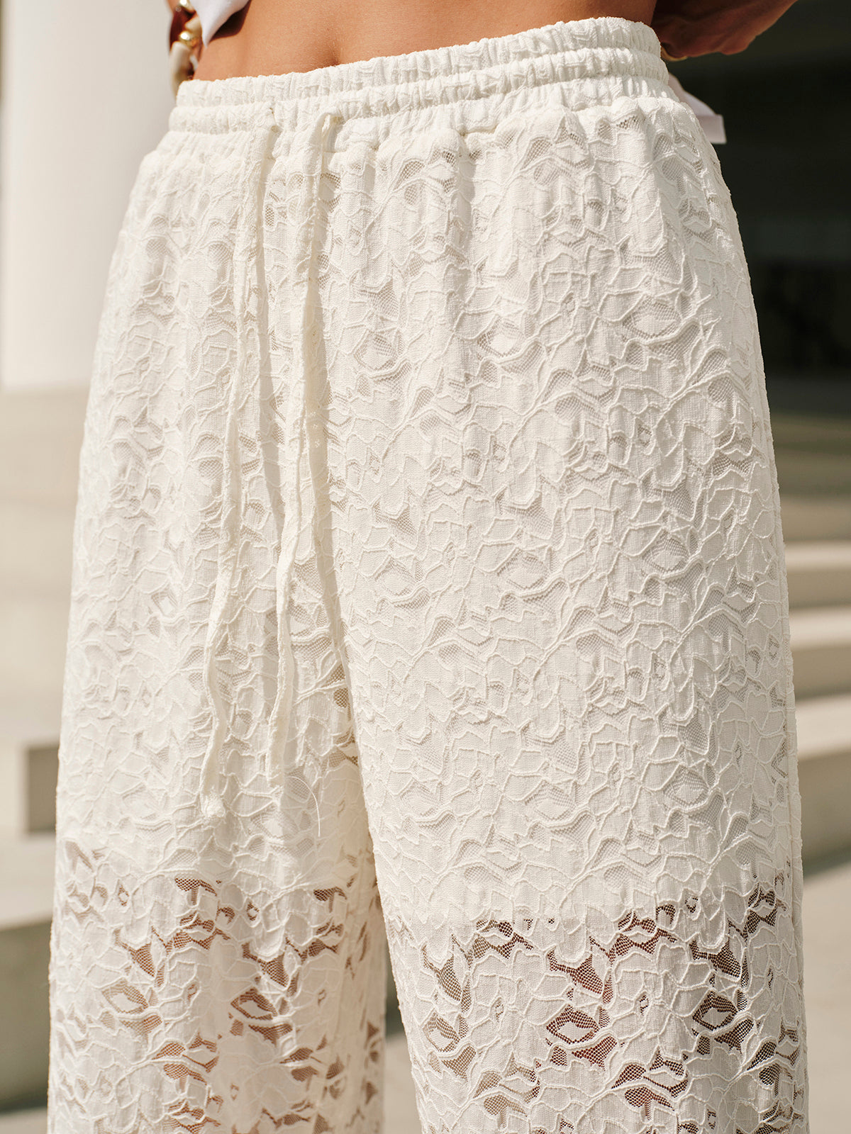 White lace pants with floral pattern close-up detail