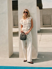 Cream crochet vest with floral pattern worn with white pants