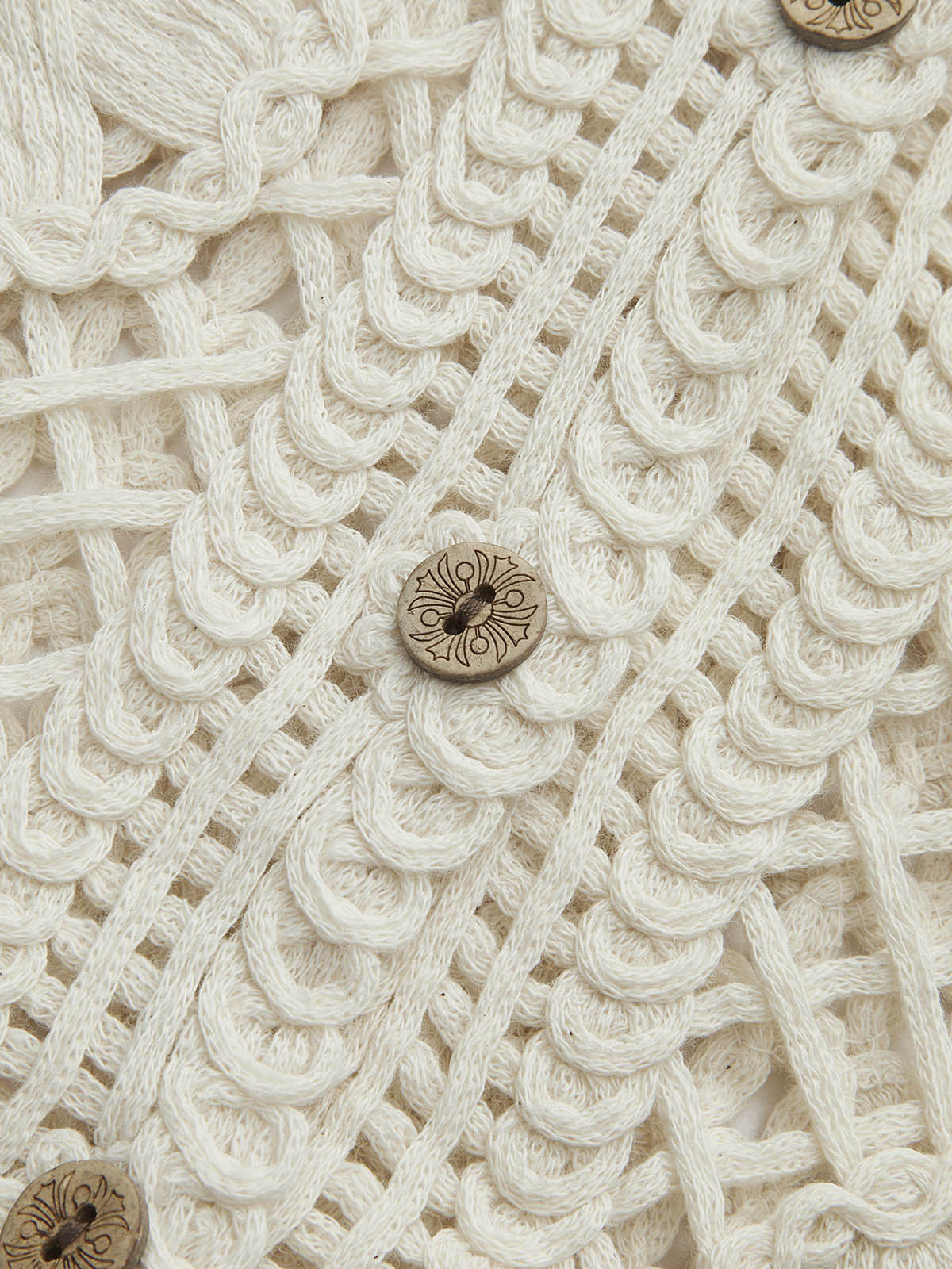 Close-up of cream crochet vest buttons and pattern detail