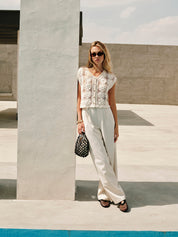 Cream crochet vest with floral pattern worn with white pants and accessories