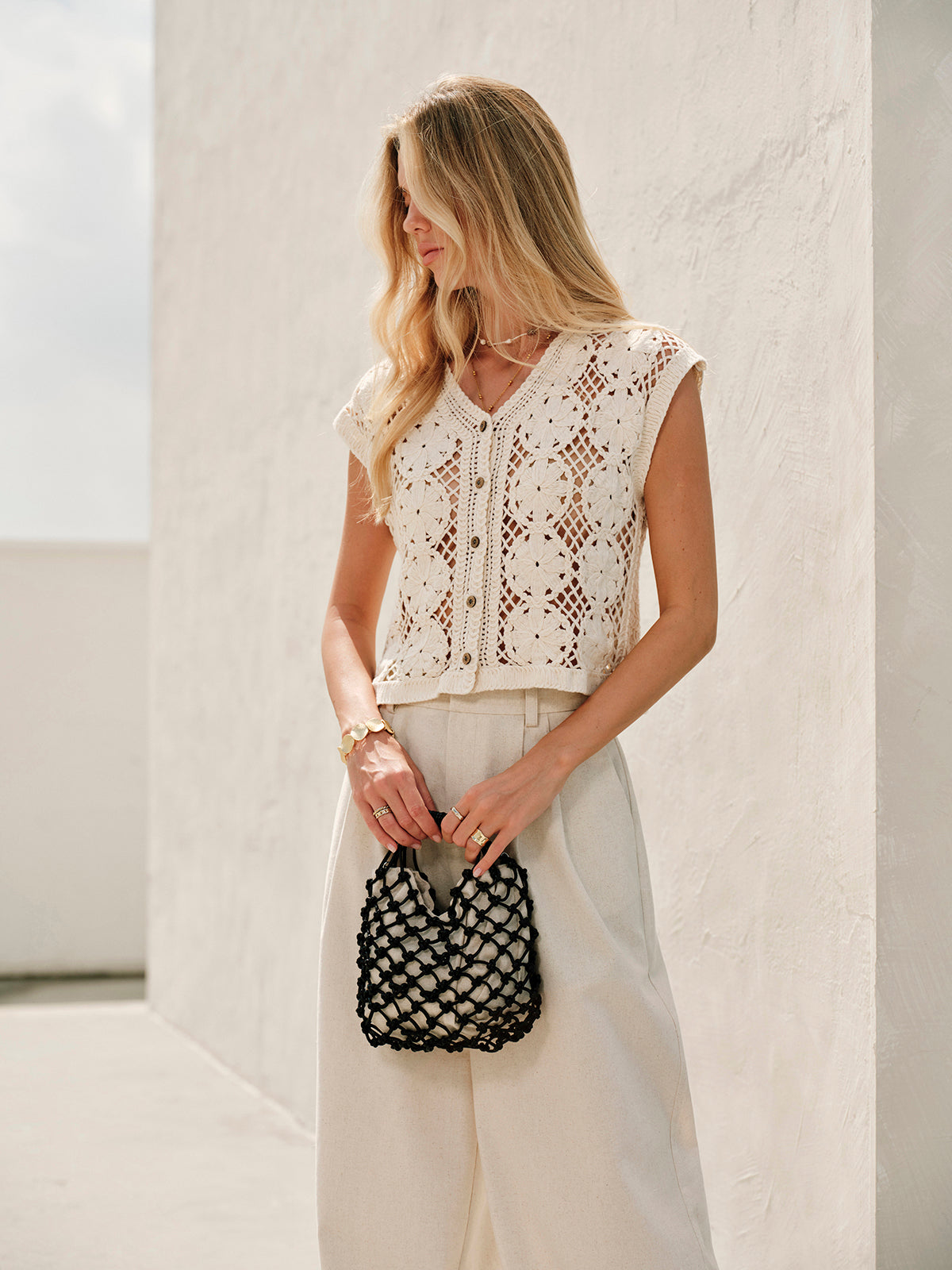 Cream crochet vest with floral pattern worn with black mesh bag