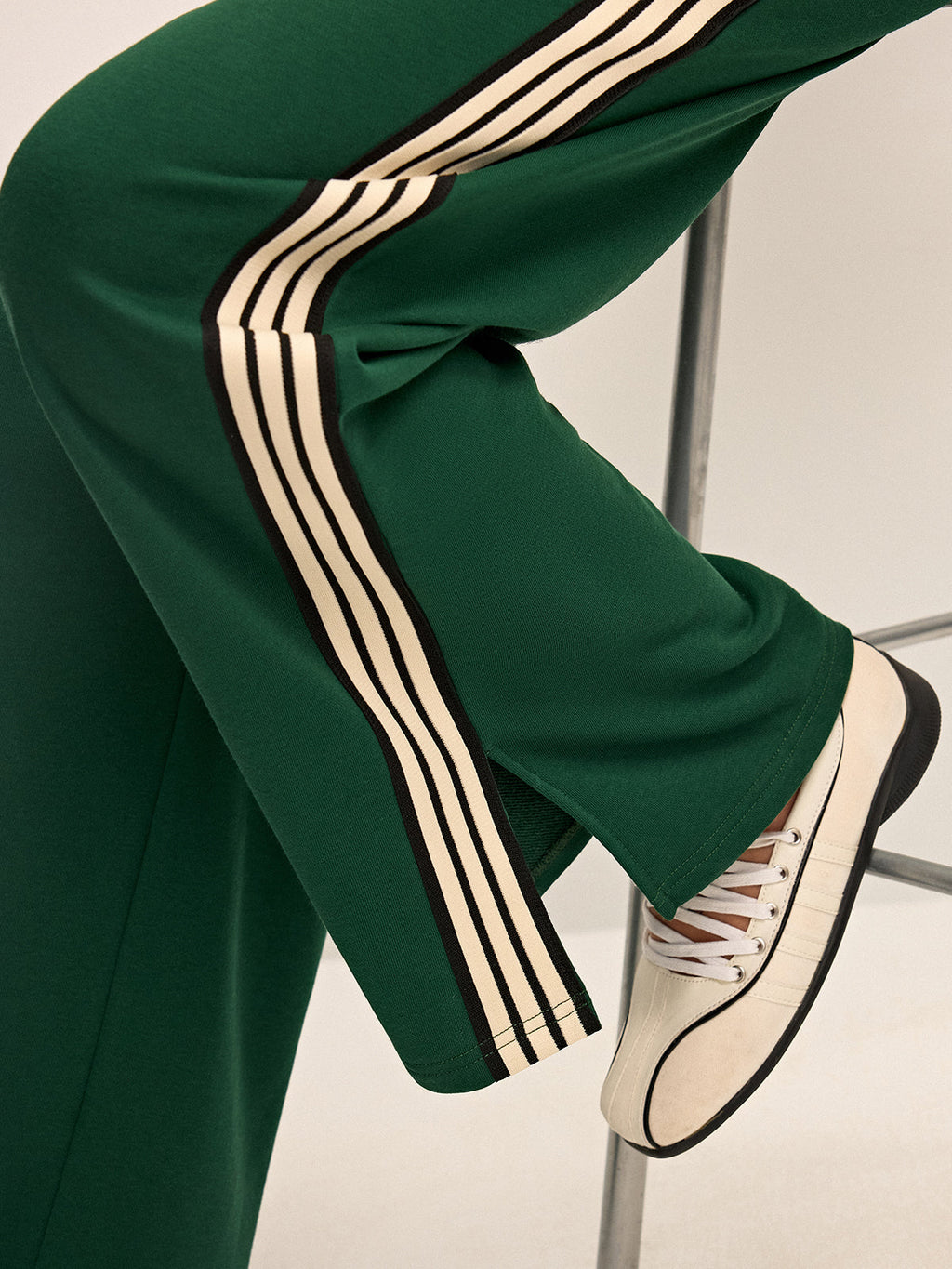 Green joggers with white and black stripes close-up leg detail