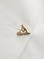 Gold button detail on white V-neck top, close-up