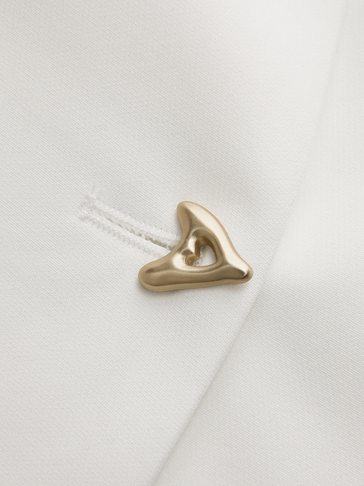 Gold button detail on white V-neck top, close-up