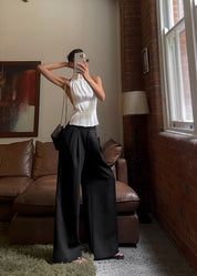 White pleated halter top worn with black pants and chain strap full body view