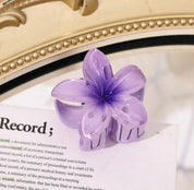 Purple flower-shaped hair clip with gradient petals on a book page.