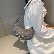 Shoulder bag gray with silver buckles worn on shoulder