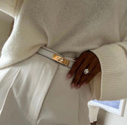 White leather belt with gold buckle worn with white dress