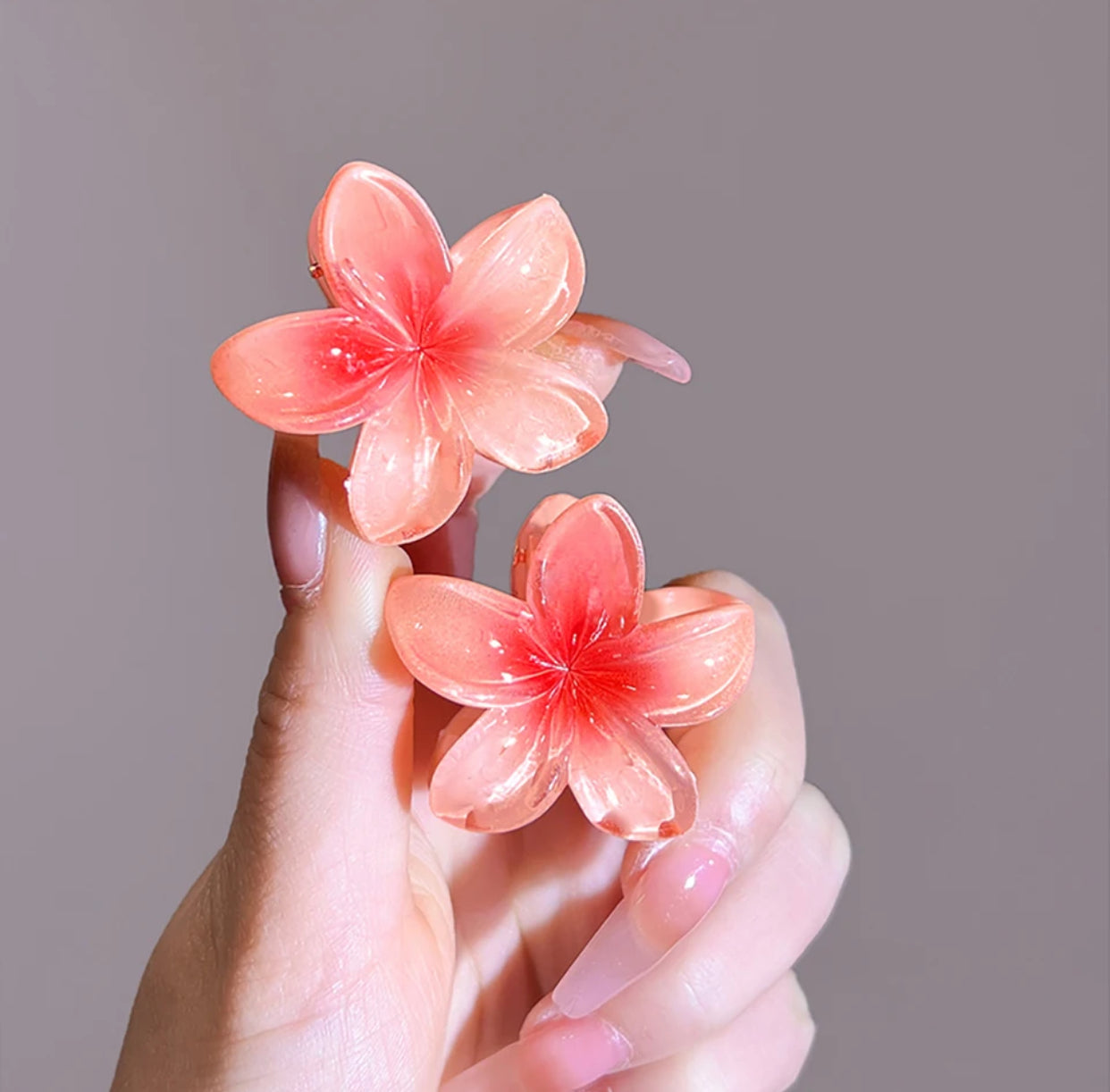 Orange flower-shaped hair clips held in hand.