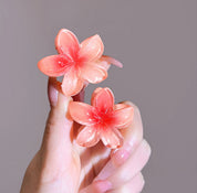 Orange flower-shaped hair clips held in hand.