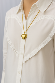 Gold heart pendant necklace worn on white blouse front view