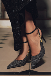 Black studded pumps with ankle strap and gold detail, side view
