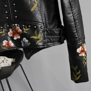 Black leather jacket with floral embroidery and studs, close-up of sleeve and side