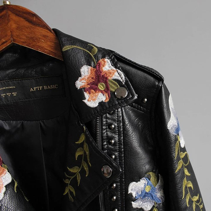 Black leather jacket with floral embroidery and studs, close-up of collar
