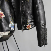 Black leather jacket with floral embroidery and studs, close-up of front zipper and studs