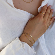 Gold-colored snake chain bracelet worn on wrist, side view