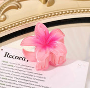Pink flower-shaped hair clip with gradient petals on a book page.