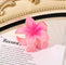 Pink flower-shaped hair clip with gradient petals on a book page.