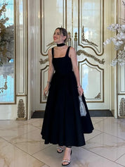 Black fit-and-flare dress side view on model indoors