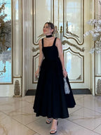 Black fit-and-flare dress side view on model indoors