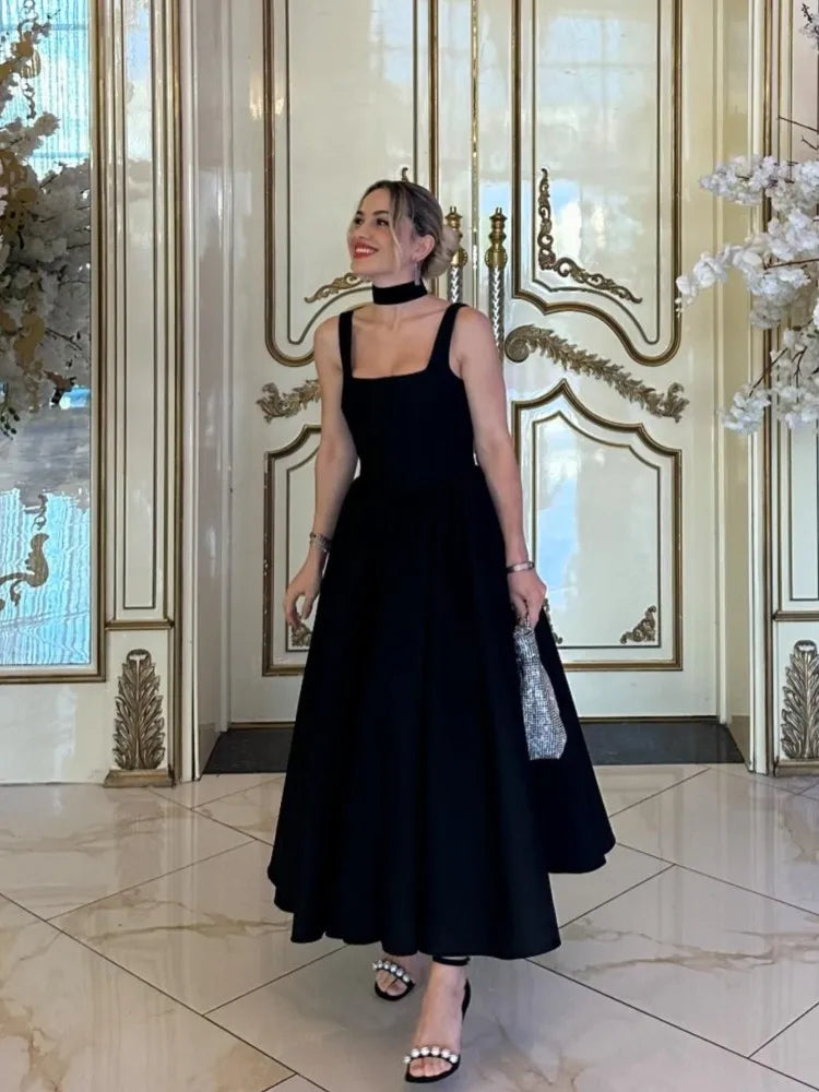 Black fit-and-flare dress side view on model indoors