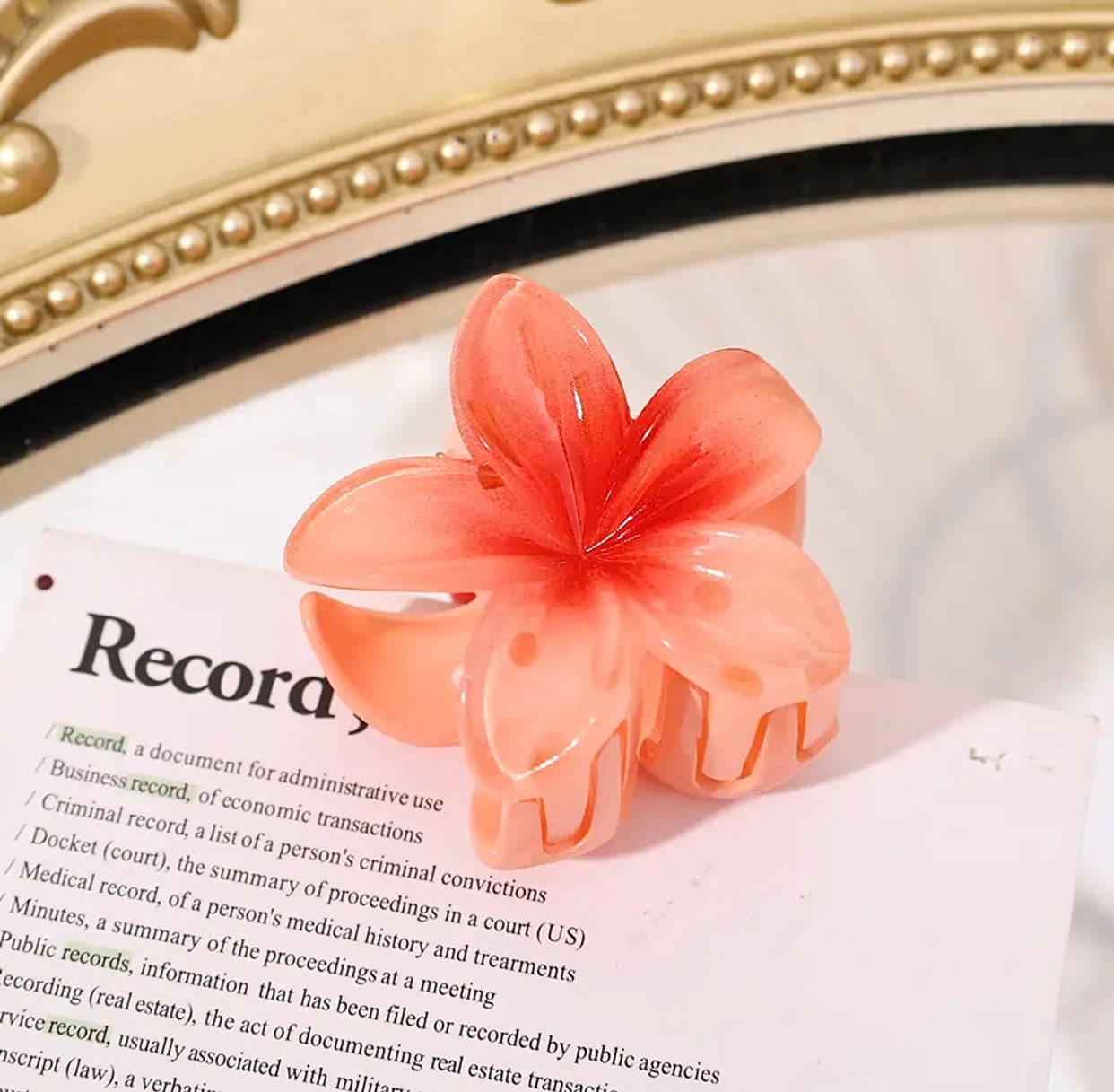 Orange flower-shaped hair clip with gradient petals on a book page.