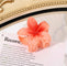 Orange flower-shaped hair clip with gradient petals on a book page.
