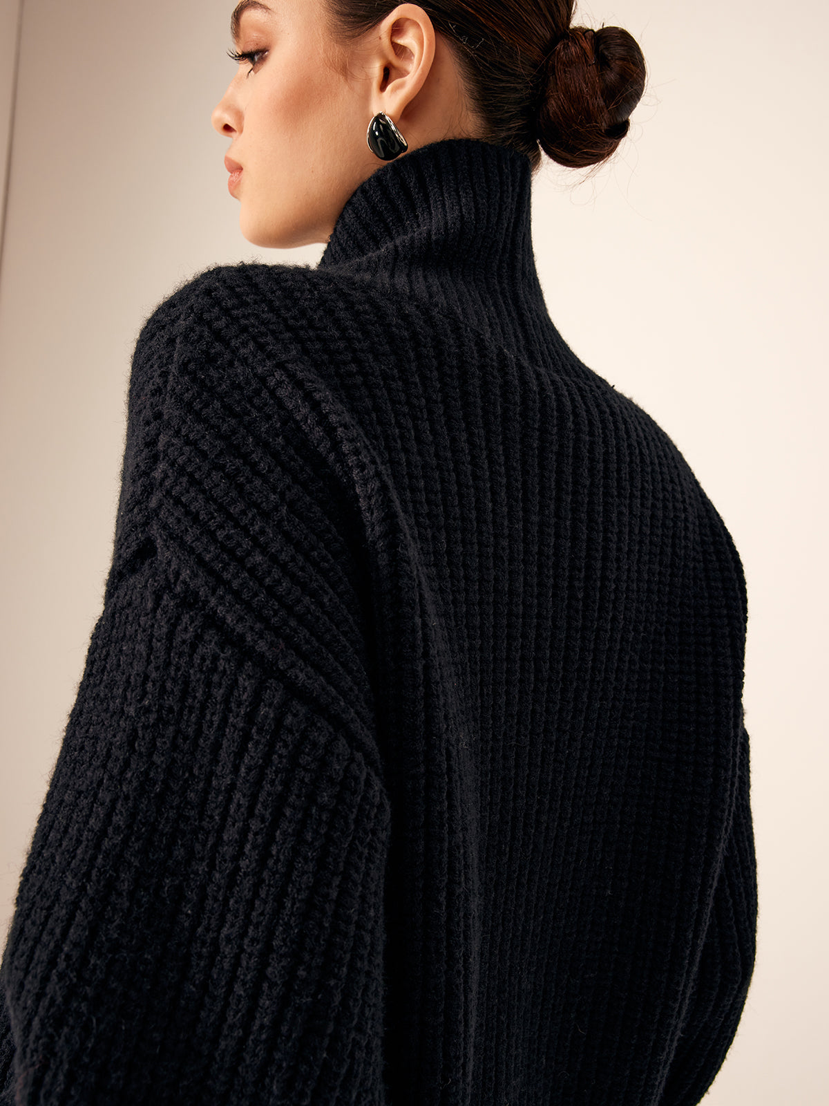 Side view of black chunky knit cardigan with high collar