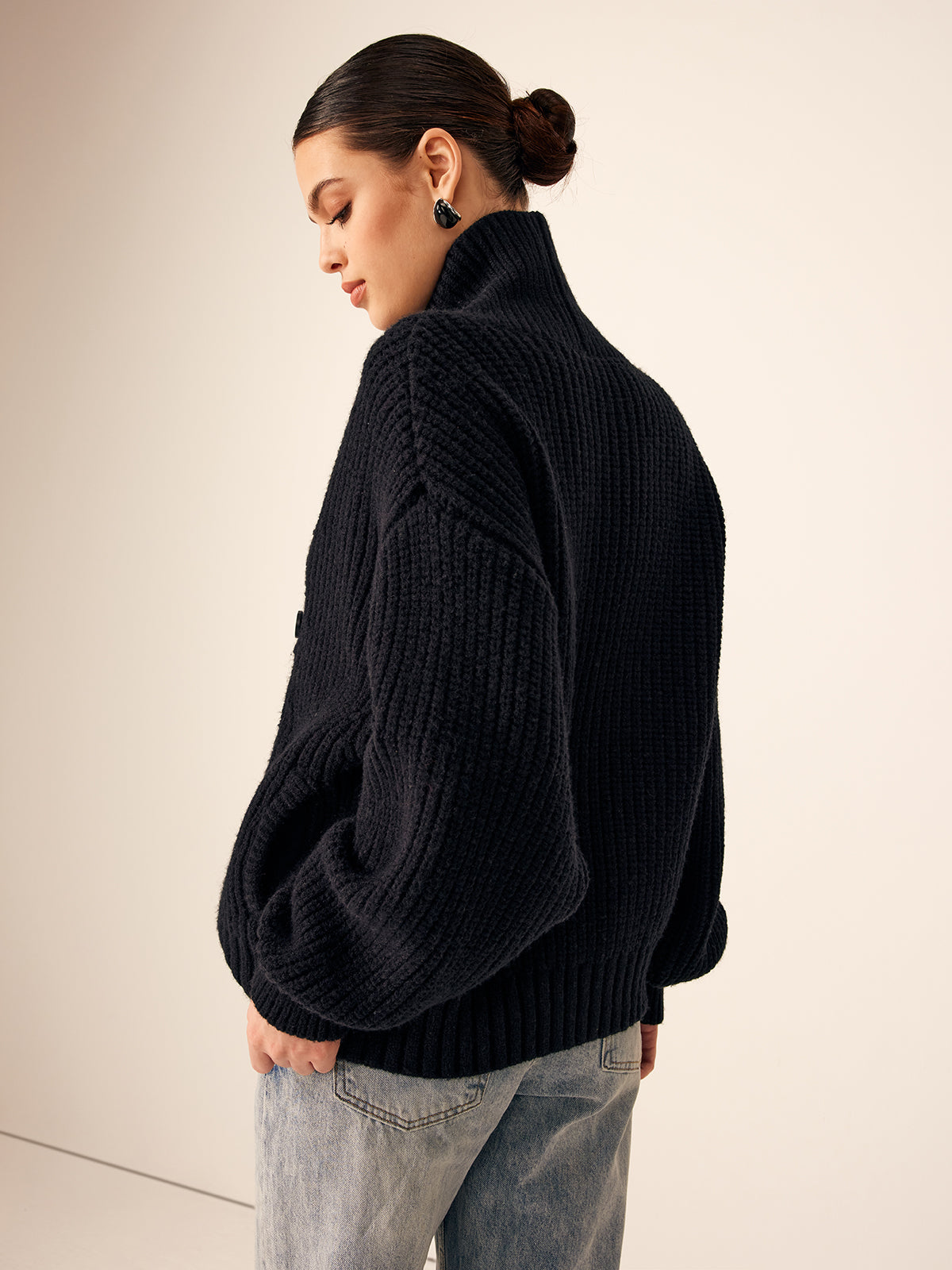 Back view of black chunky knit cardigan with high collar