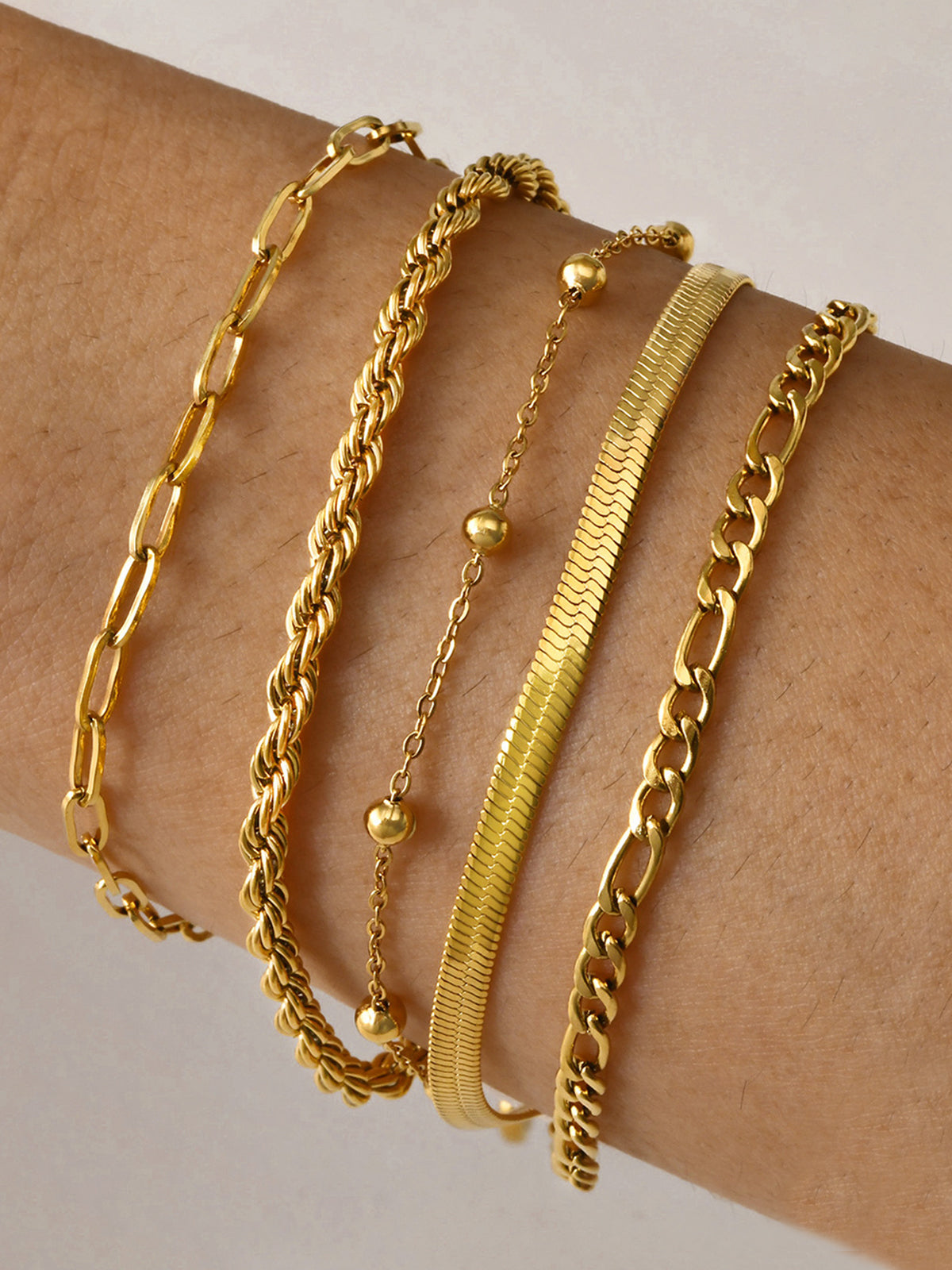 Gold armband set with various chain styles worn on wrist