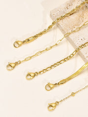 Gold armband set with various chain styles laid flat on surface