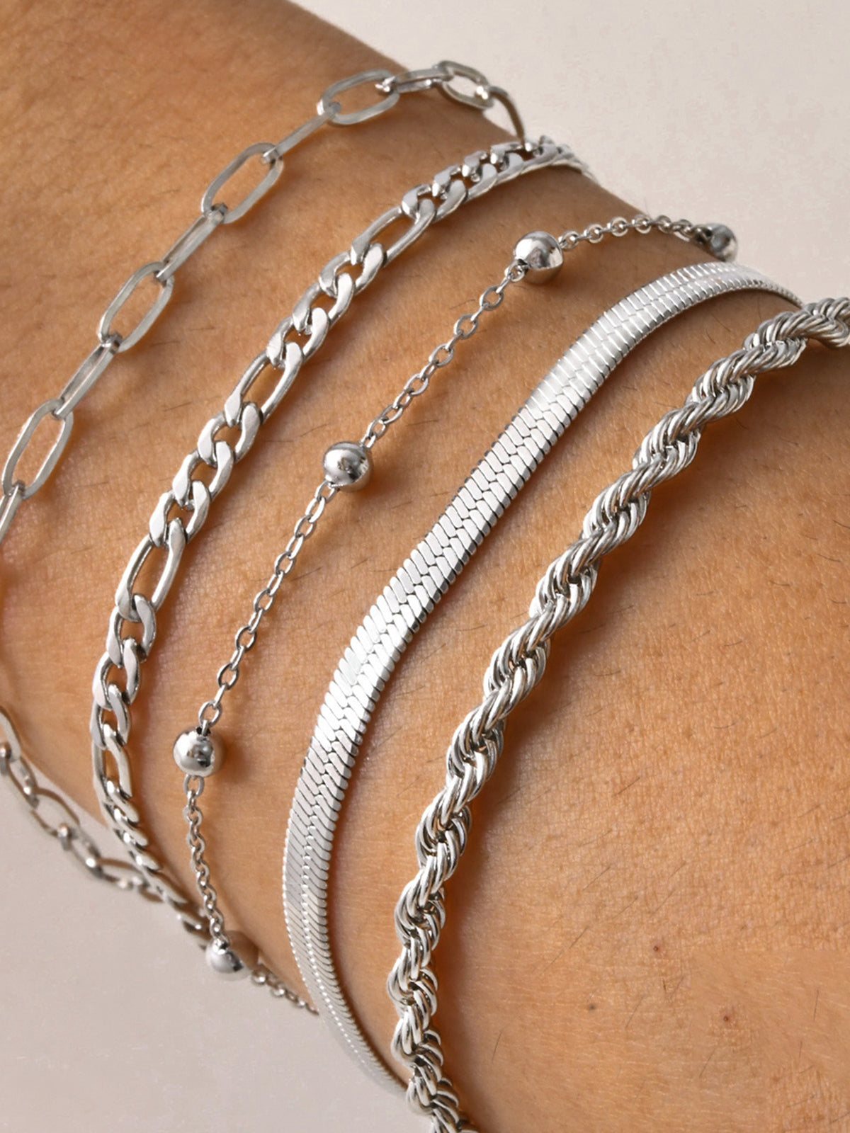 Silver armband set with various chain styles worn on wrist