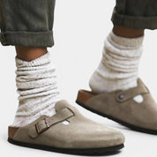 Beige suede clogs worn with white socks and rolled-up pants