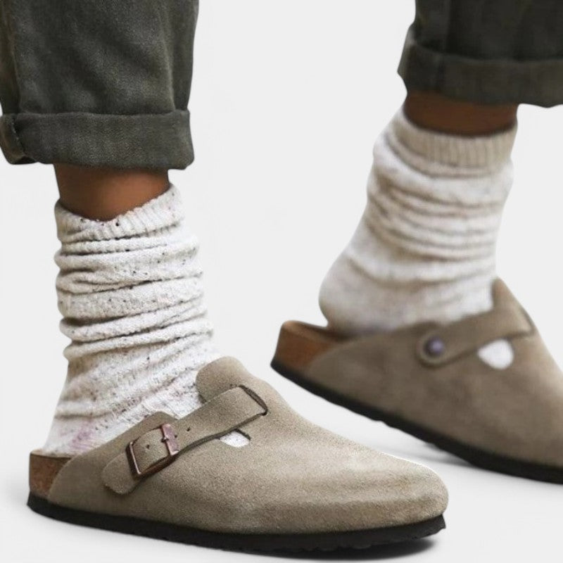 Beige suede clogs worn with white socks and rolled-up pants