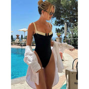 Eenstuk zwempak zwart met witte details, zijaanzicht bij zwembad