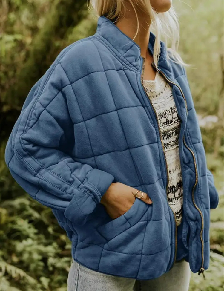 Blauwe tussenjas met blokpatroon, vrouw draagt hand in zak