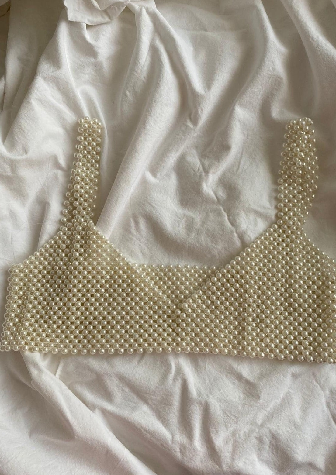 Synthetic pearl bralette laid flat on white fabric