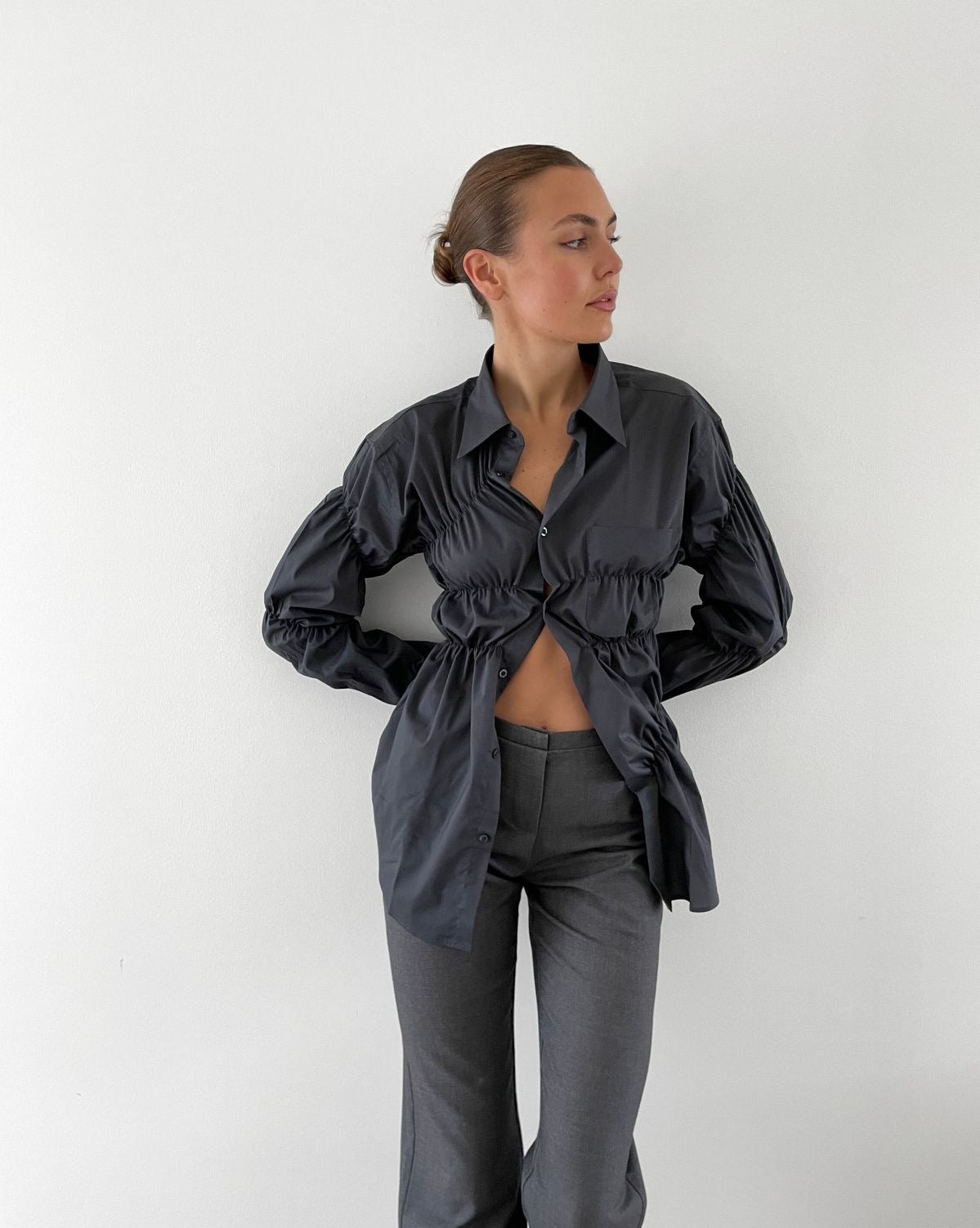 Blouse with ruched detailing and puff sleeves, side view with black pants
