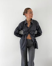 Blouse with ruched detailing and puff sleeves, side view with black pants