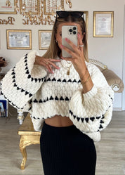 Cream chunky knit sweater with black heart pattern, worn with black shorts, front view