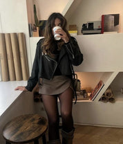 Luxe skort beige met zwart jasje en laarzen, model zittend