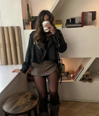 Luxe skort beige met zwart jasje en laarzen, model zittend